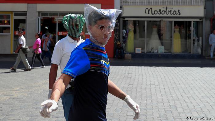 dos hombres cubren sus rostros con bolsas de plástico en Carcacas, para protegerse del coronavirus.